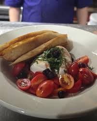 Caprese burrata salad with cherry tomatoes, olives, basil, and breadsticks