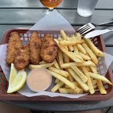 Fish and chips with fries, lemon wedges, and dipping sauce